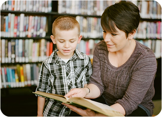 Enseignante accompagnant un élève à la bibliothèque, illustrant le rôle du corps enseignant dans l’organisation scolaire
