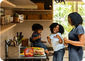 Parent et enfants préparant un repas dans la cuisine, symbolisant l’autonomie des familles pour la gestion des repas scolaires.